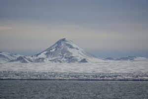 picture of snowy mountain and cold ocean on the reykjanes penisular, iceland.
