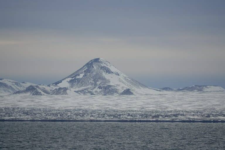 picture of snowy mountain and cold ocean on the reykjanes penisular, iceland.