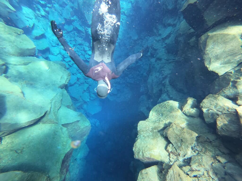 Snorkeling in Iceland. Silfra snorkeling - man free diving in a wet suit in very blue turquoise water.