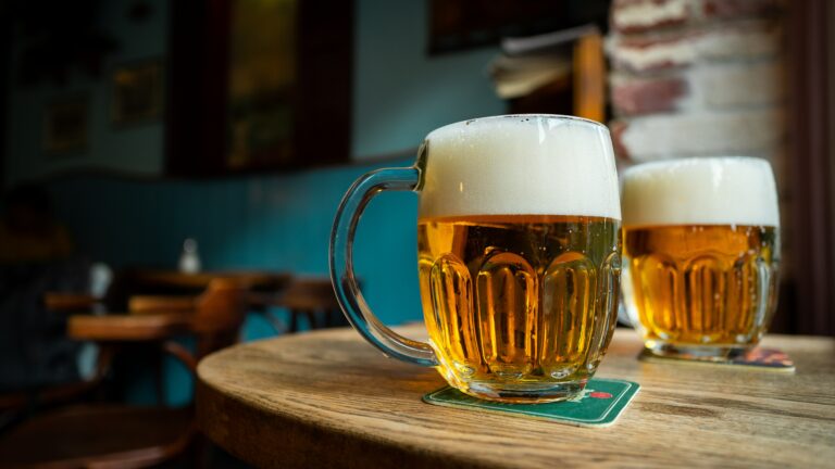 a pint of beer with way to much foam sits on a bar table, presumably to be drunk on beer day in Iceland.